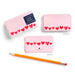 Pink notepad with heart designs and an orange pencil on a white background
