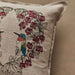 Decorative pillow with embroidered hummingbird and floral design on a beige background