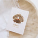 A white greeting card featuring a cartoon turkey with a fanned tail and the words 'GOBBLE GOBBLE' below, styled on a light wood tray with a white textured cloth.