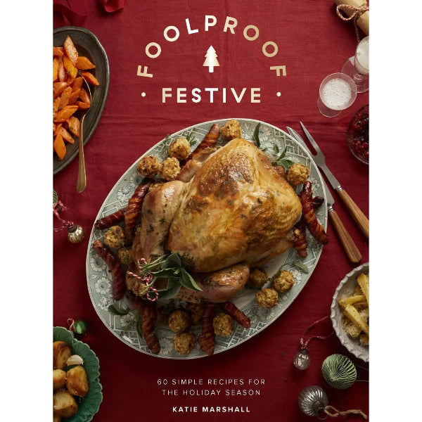 A festive holiday cookbook cover titled 'FOOLPROOF FESTIVE' by Katie Marshall, featuring a roasted turkey on an oval platter with roasted carrots and stuffing on a deep red tablecloth background.
