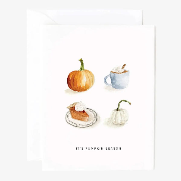 A white greeting card with a watercolor autumn pumpkin theme, featuring an orange pumpkin, a blue mug with whipped cream and cinnamon, a slice of pumpkin pie on a plate, and a small white pumpkin. The text 'IT'S PUMPKIN SEASON' is printed at the bottom.