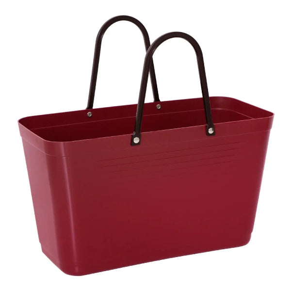 A red plastic utility shopping basket with two black metal handles attached by silver rivets, shown on a plain white background.