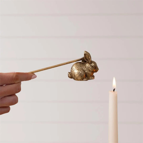 Gold rabbit-shaped candle holder being used to light a candle against a plain background