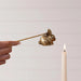 Gold rabbit-shaped candle holder being used to light a candle against a plain background