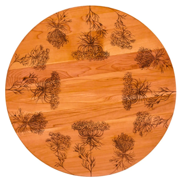 Round wooden lazy susan with engraved floral patterns on a white background
