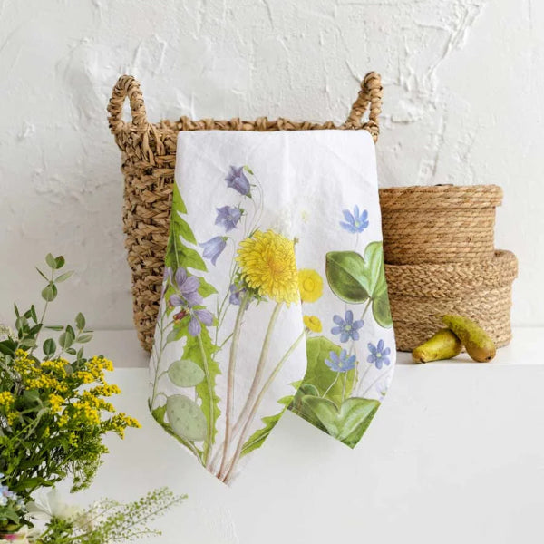 Floral towel on a white surface with wicker baskets and greenery.
