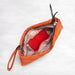 Orange quilted handbag with a red interior on a white background