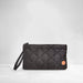 A black quilted nylon wristlet clutch with a matching wrist strap and a small circular orange logo patch, set against a light gray studio background.