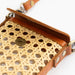 Close-up of a handbag with woven pattern and brown leather trim on a white background