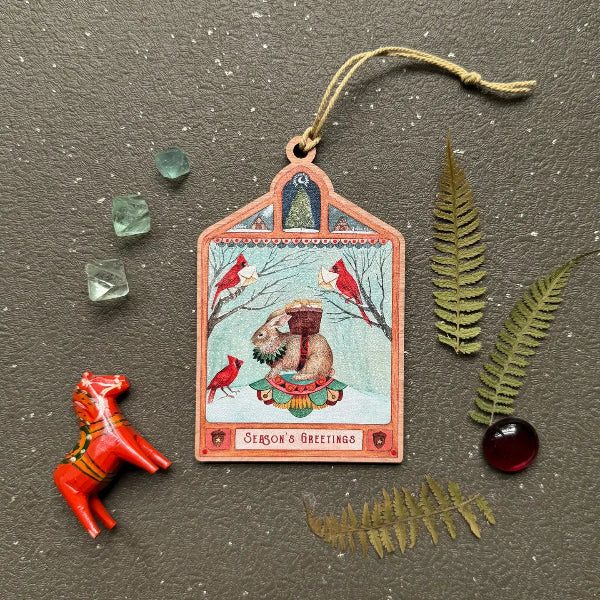 Decorative card with animals and 'Season's Greetings' text, surrounded by decorative elements on a textured surface.
