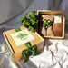 Gift set with plants, scissors, and a card on a white fabric background
