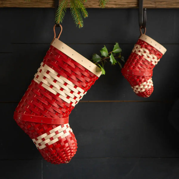 Two red and white wicker Christmas stockings hanging against a dark background.