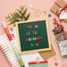 Letter board with colorful text on a pink background with festive items