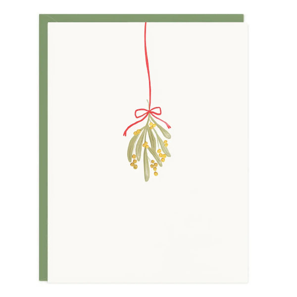 A minimalist holiday greeting card with an off-white front, featuring a watercolor illustration of mistletoe with green leaves, small yellow berries, and a red ribbon. The card is shown with a muted sage green envelope behind it on a clean white background.