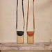 Two woven handbags with leather accents on a wooden surface against a beige wall.