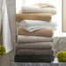 Stack of folded towels in various colors on a bathroom shelf with decorative elements.