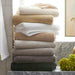 Stack of folded towels in various colors on a bathroom shelf with decorative elements.