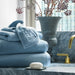 Stack of blue towels with a soap bar and decorative elements in a bathroom setting