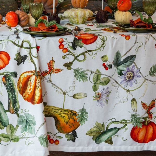 Tablecloth with autumnal design featuring pumpkins and gourds on a table setting.