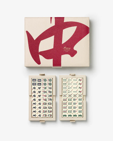 Mahjong set with open case revealing tiles and closed box with red logo on beige background