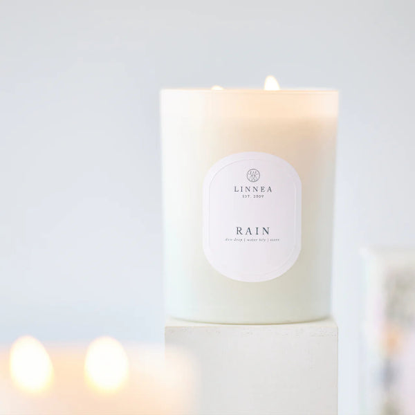 Candle labeled 'LINNEA Rain' on a light background
