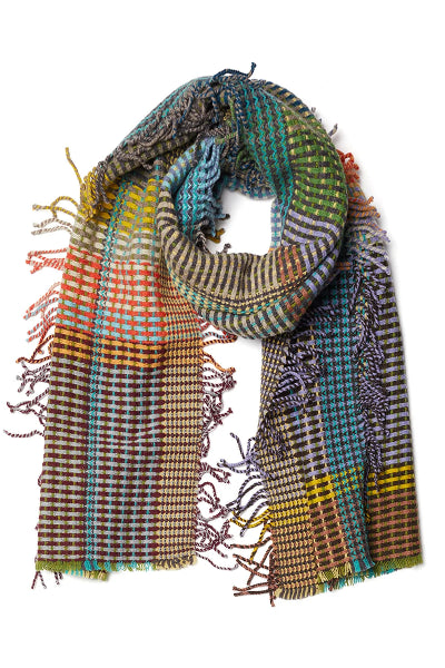 A multicolor woven scarf with fringe details, featuring a plaid and houndstooth pattern in shades of green, blue, brown, orange, yellow, and purple on a white background.