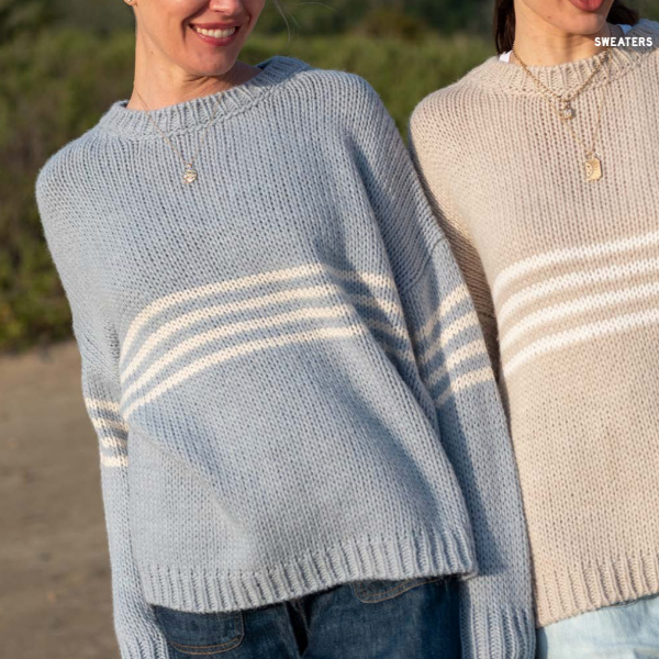 Two people wearing striped sweaters outdoors with a blurred background