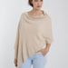 Woman wearing a beige poncho over a white shirt on a light gray background