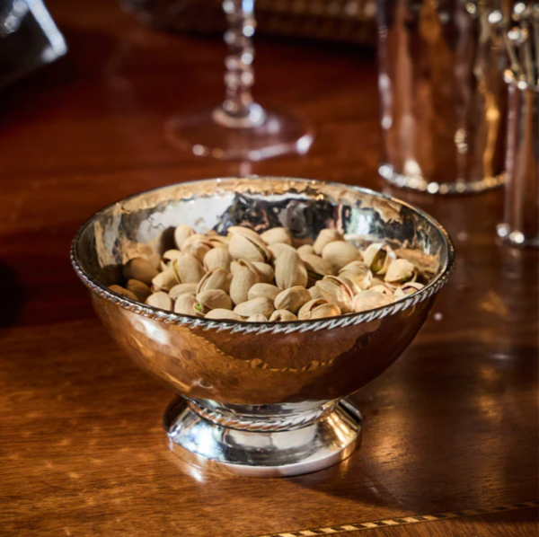 Silver bowl filled with pistachios on a wooden table