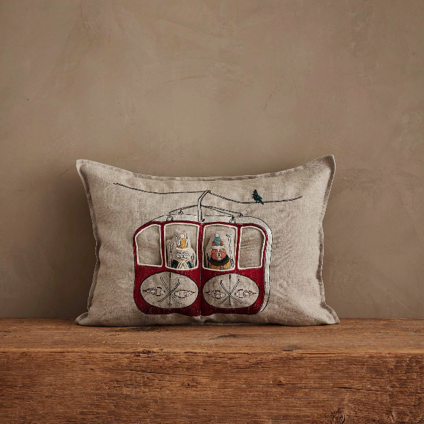 Decorative pillow with a cable car design on a wooden surface against a beige wall