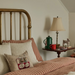 Bedroom with brass headboard, striped bedding, and side table with lamp and mug.