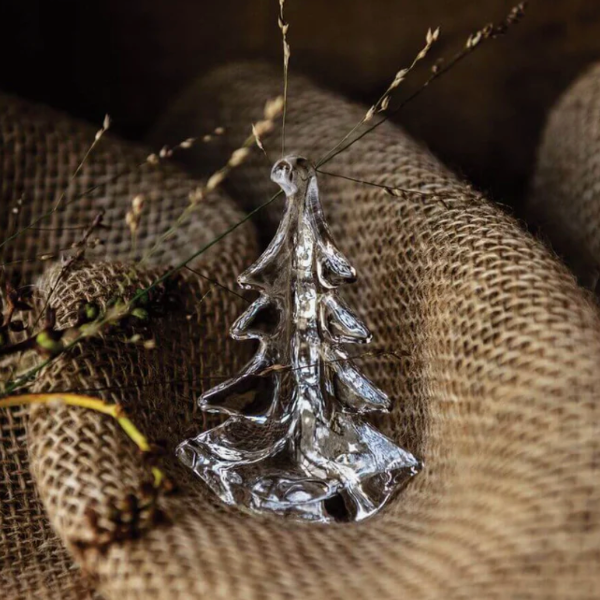 Silver tree-shaped ornament on a textured brown fabric background