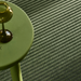 Green side table with a gold candle holder on a textured green carpet