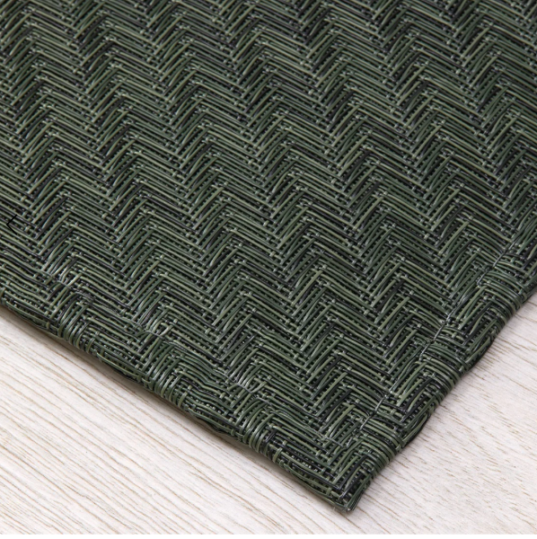 Dark green textured rug with a herringbone pattern on a light wooden floor.