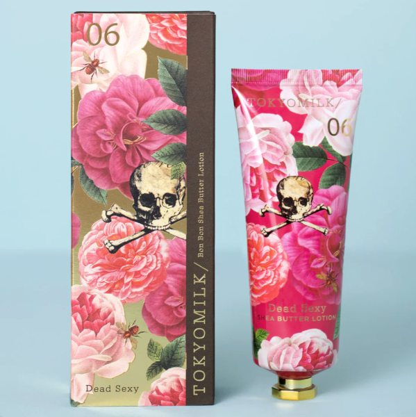TOKYOMILK Dead Sexy lotion tube and packaging with floral design and skull illustration on a light blue background.