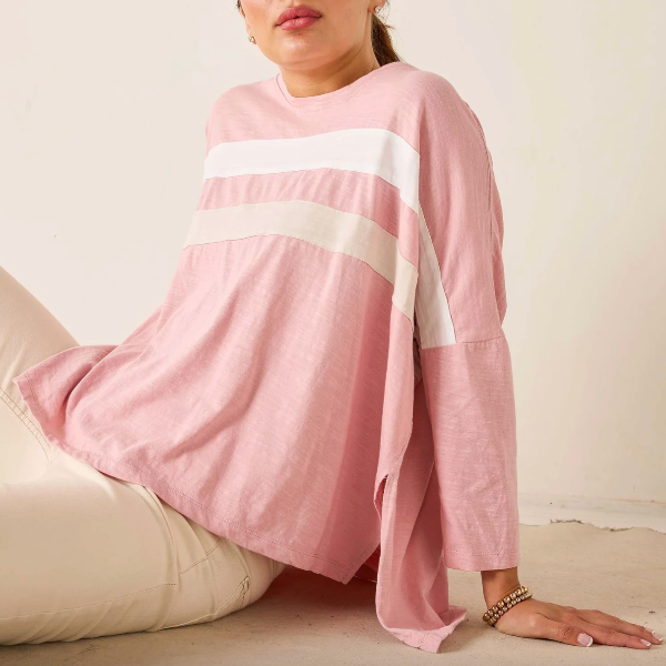 Person wearing a pink and white striped sweater sitting on a beige couch.