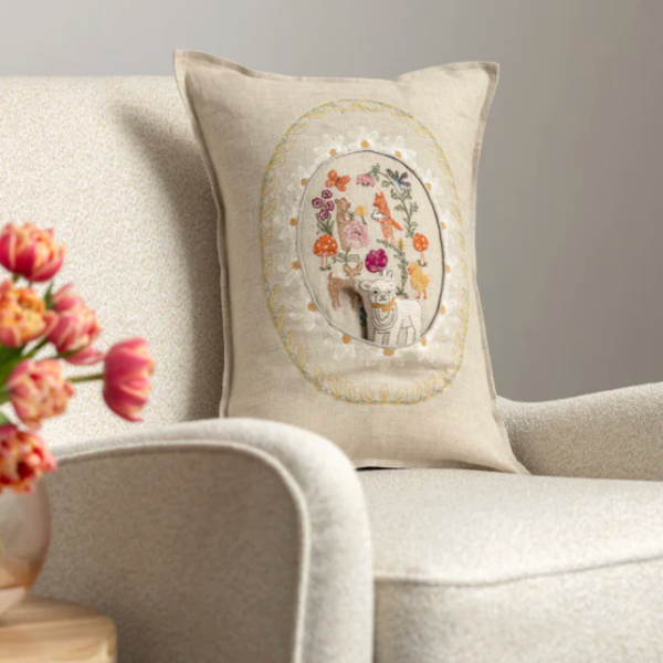 Decorative pillow with floral embroidery on a beige sofa with tulips.