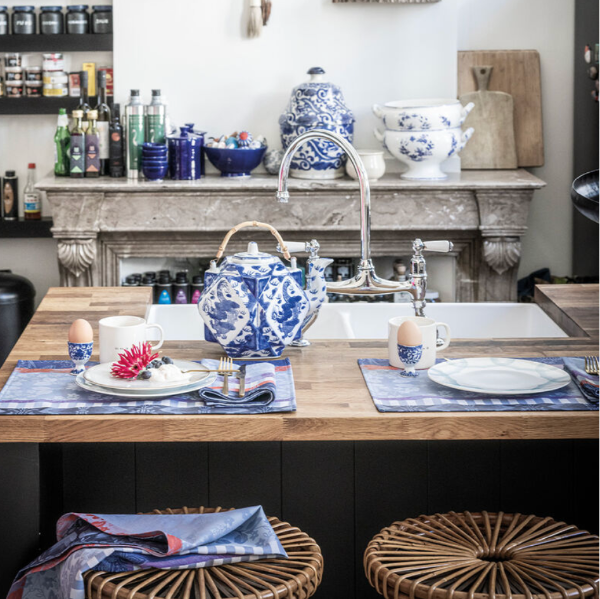Kitchen with wooden island, blue and white teapot, and various kitchen items.