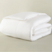 Folded white comforter on a beige background