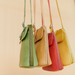 Four colorful leather handbags hanging against a beige background