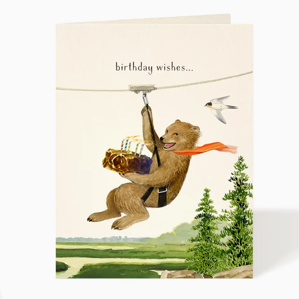 Birthday card with a bear in a safety harness and a bird, set against a scenic background.