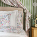 Bedroom with floral bedding and curtains against a green striped wall.