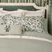 Bed with green and white striped bedding and floral-patterned pillows.
