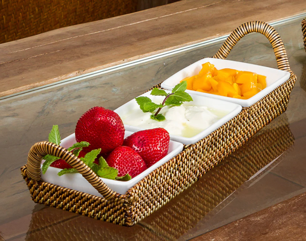 Fruit platter with strawberries, pineapple, and mint leaves on a woven tray.