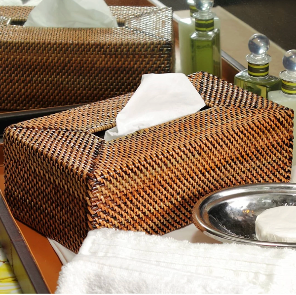 Woven tissue box holder with tissues on a table with soap and towel.