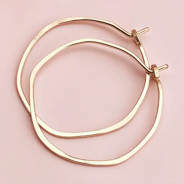 Gold hoop earrings on a pink background