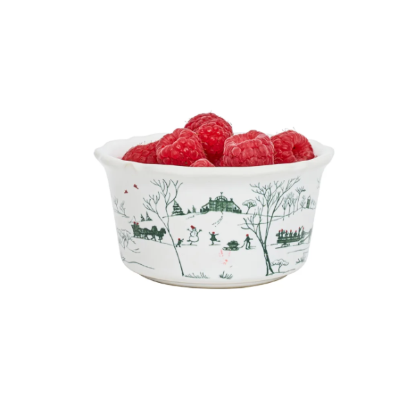 A white ceramic bowl with a green winter landscape print, filled with fresh red raspberries, set against a plain white background.