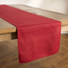 A red table runner with a scalloped edge draped over a rustic wooden table on a wooden floor.
