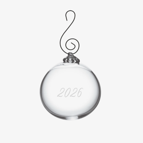 A clear glass ornament with a black wire hanger shaped like a musical eighth note and the year '2026' etched on the front, shown against a plain white background.