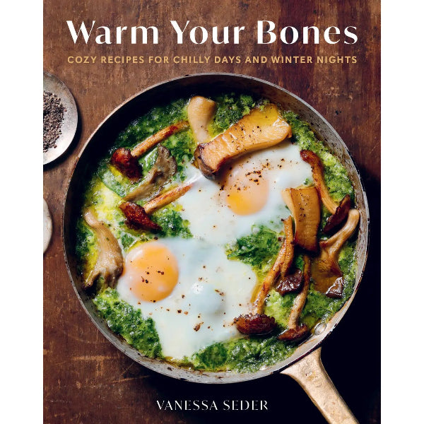 Book cover of 'Warm Your Bones' with a pan of eggs and greens on a wooden background